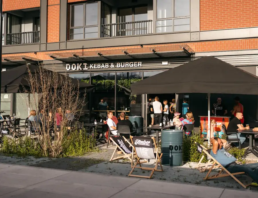 Lokal DOKI w parterze nowego budynku z ogródkiem pod parasolami