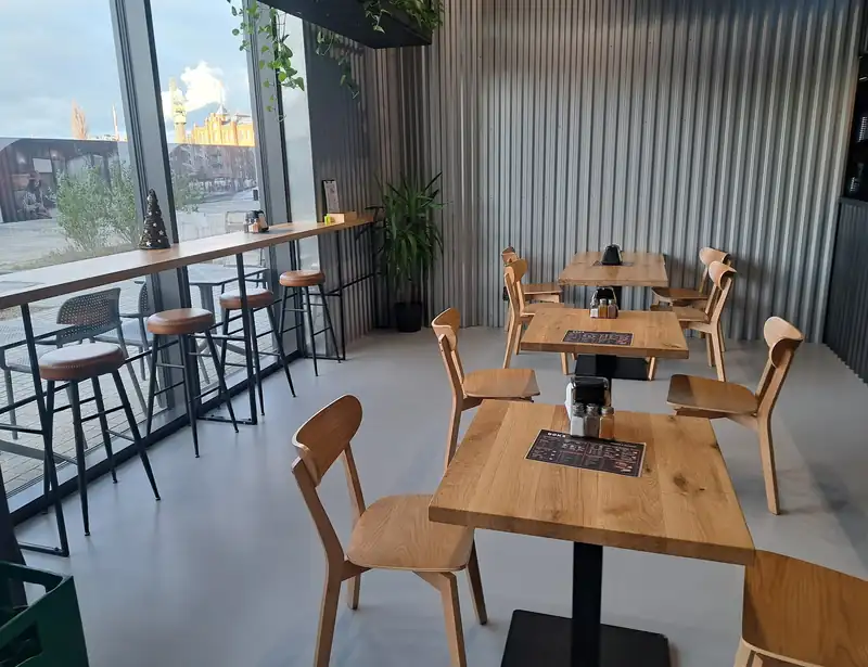 Sala z drewnianymi stolikami i dużymi oknami